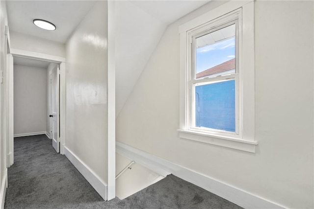 hall featuring dark carpet and vaulted ceiling