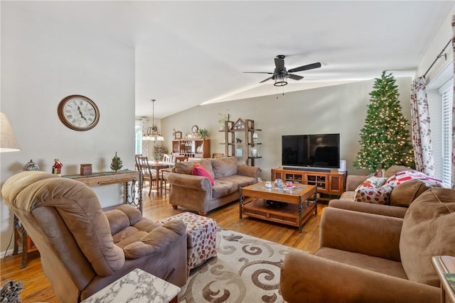 living room with ceiling fan with notable chandelier, light hardwood / wood-style floors, and lofted ceiling