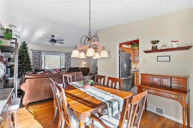 dining space featuring light hardwood / wood-style floors and ceiling fan with notable chandelier