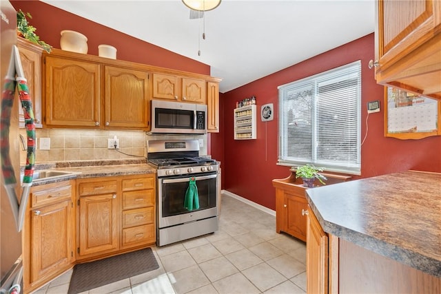 kitchen with decorative backsplash, light tile patterned flooring, stainless steel appliances, and vaulted ceiling