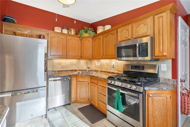 kitchen featuring backsplash, dark stone counters, sink, light tile patterned floors, and appliances with stainless steel finishes