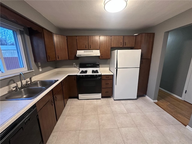 kitchen featuring dark brown cabinets, white appliances, light hardwood / wood-style flooring, and sink