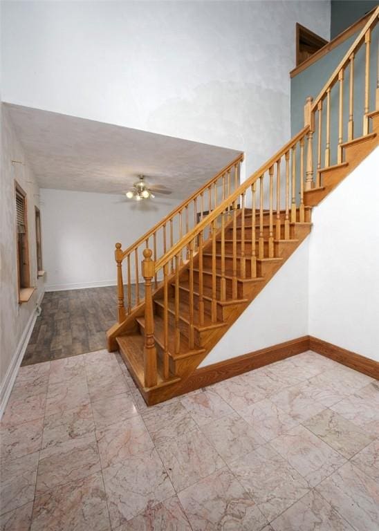 stairway featuring ceiling fan