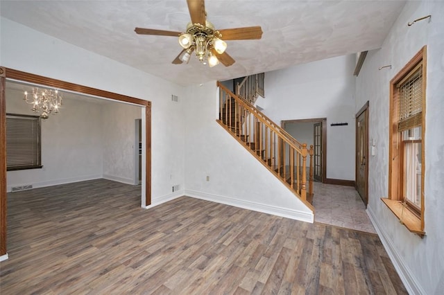 unfurnished living room with ceiling fan with notable chandelier and dark hardwood / wood-style flooring