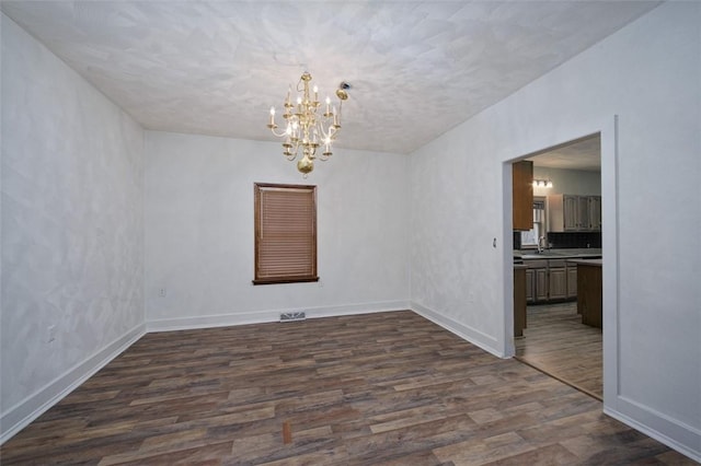 empty room featuring sink, dark hardwood / wood-style flooring, and a notable chandelier