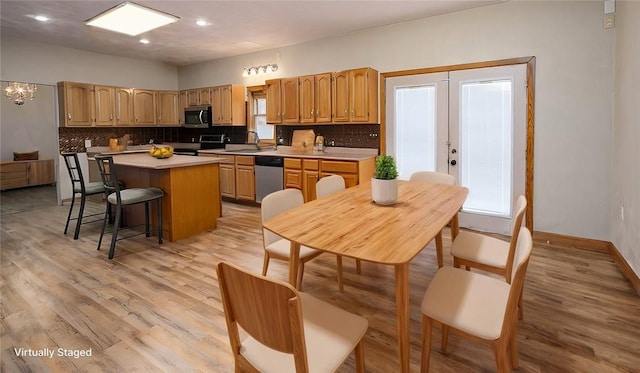 kitchen featuring sink, a center island, stainless steel appliances, light hardwood / wood-style floors, and decorative backsplash