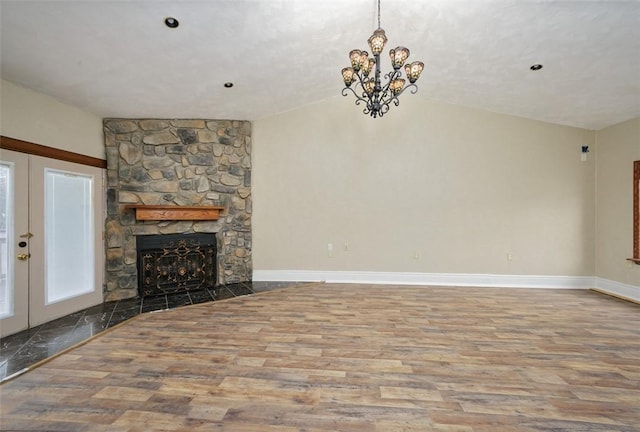 unfurnished living room with hardwood / wood-style floors, vaulted ceiling, french doors, and a stone fireplace