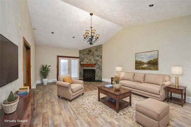 living room featuring french doors, an inviting chandelier, light hardwood / wood-style flooring, a fireplace, and lofted ceiling