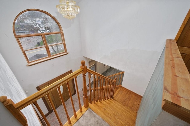 staircase featuring hardwood / wood-style floors and an inviting chandelier