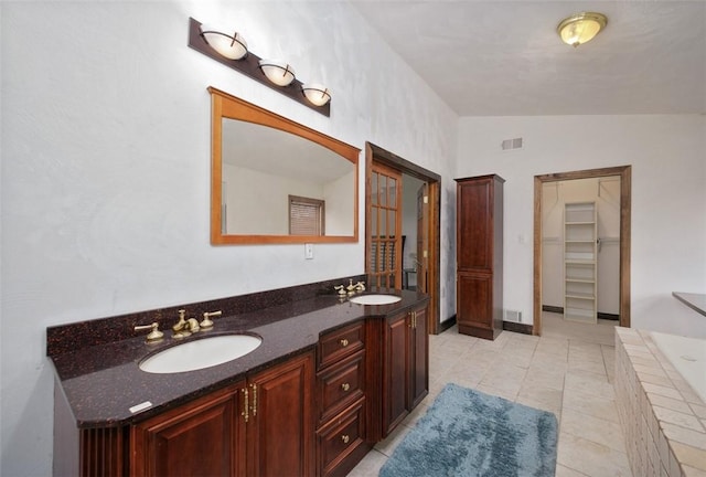 bathroom with tile patterned floors, vanity, a relaxing tiled tub, and vaulted ceiling