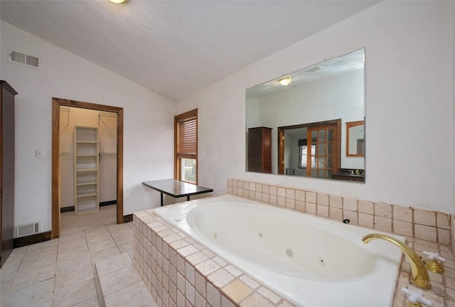 bathroom with tile patterned floors, lofted ceiling, and tiled tub