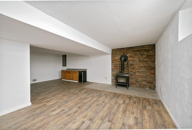 unfurnished living room with wood-type flooring and a wood stove