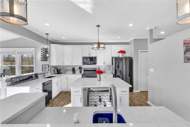 kitchen with a center island, black appliances, sink, hanging light fixtures, and white cabinetry