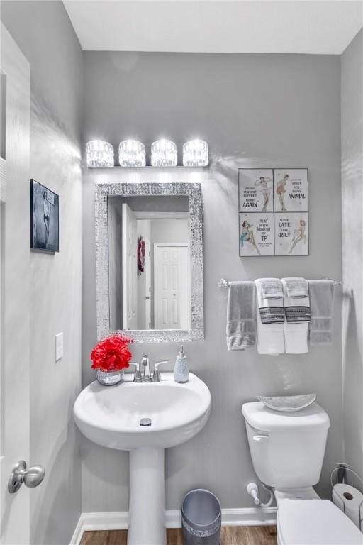 bathroom with toilet, wood-type flooring, and sink