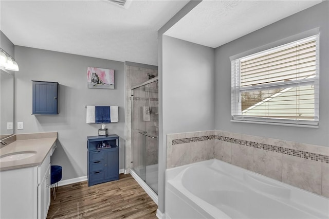 bathroom with wood-type flooring, vanity, and shower with separate bathtub