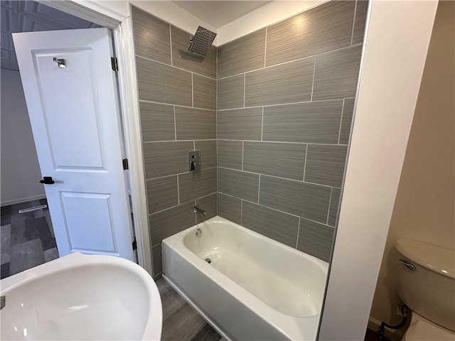 bathroom with hardwood / wood-style flooring, toilet, and tiled shower / bath