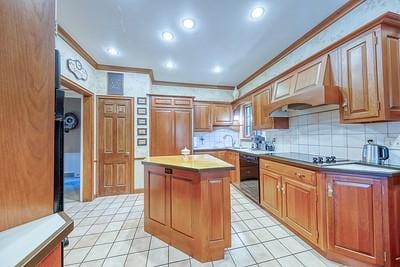 kitchen with tasteful backsplash, ornamental molding, a kitchen island, black appliances, and custom exhaust hood