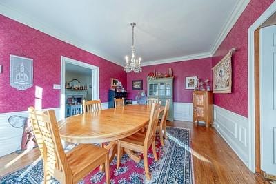 dining room with hardwood / wood-style floors, a notable chandelier, and crown molding