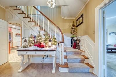 staircase featuring an inviting chandelier and ornamental molding