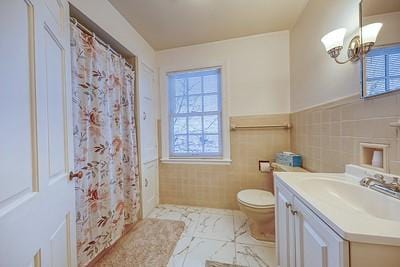 bathroom with vanity, toilet, tile walls, and a chandelier