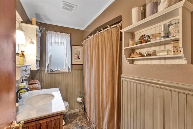 bathroom featuring a shower with shower curtain, vanity, wooden walls, crown molding, and toilet