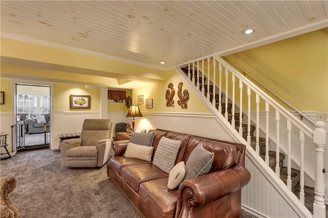 carpeted living room with ornamental molding, wooden walls, and wooden ceiling