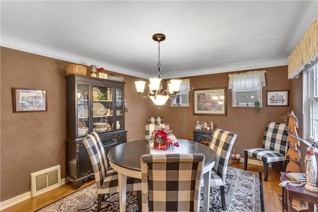 dining room featuring a chandelier, light hardwood / wood-style flooring, and crown molding