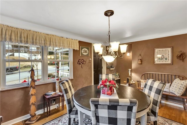 dining space with hardwood / wood-style flooring and a chandelier