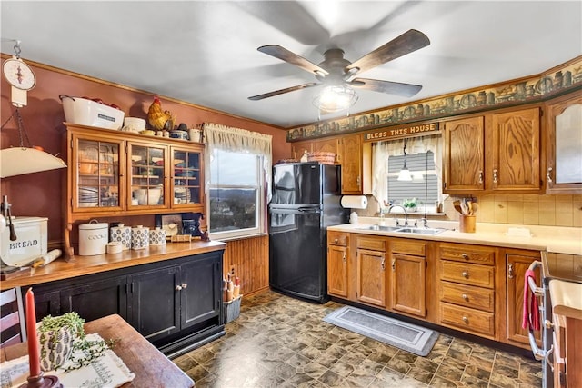 kitchen featuring black fridge, sink, ceiling fan, tasteful backsplash, and range