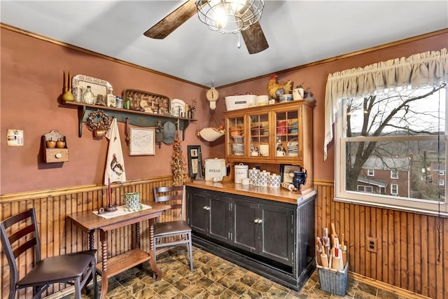 bar with ceiling fan, crown molding, and wood walls