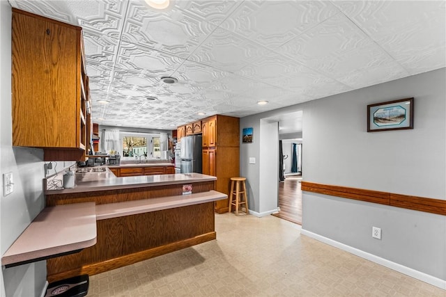 303 Water St, Jamestown, PA 16134 - kitchen featuring freestanding refrigerator, brown cabinets, a peninsula, an ornate ceiling, and a kitchen bar