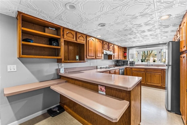 kitchen with sink, kitchen peninsula, a breakfast bar area, and appliances with stainless steel finishes