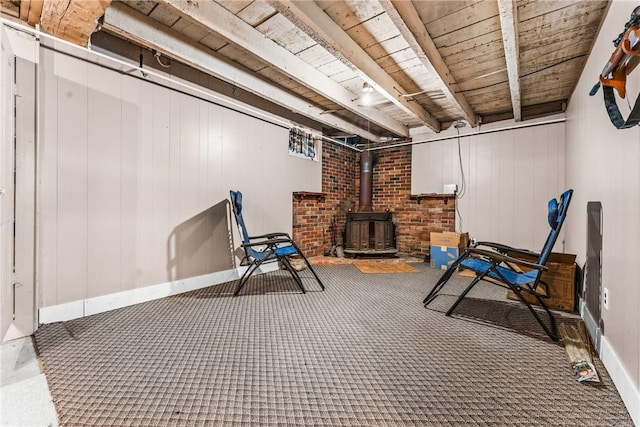 basement with a wood stove, wood walls, wood ceiling, and dark carpet