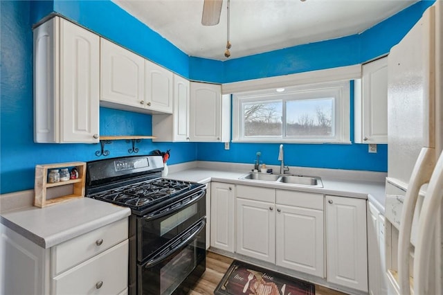 kitchen with black gas range, white refrigerator with ice dispenser, white cabinets, sink, and light hardwood / wood-style flooring