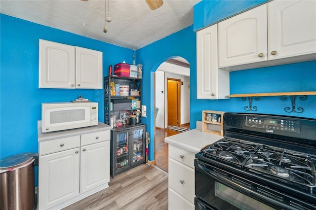 kitchen with white cabinets, light hardwood / wood-style flooring, a textured ceiling, black gas range oven, and beverage cooler