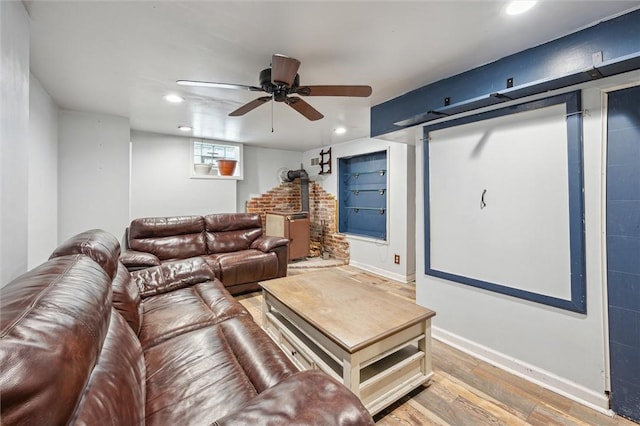 living room featuring wood-type flooring, a wood stove, and ceiling fan