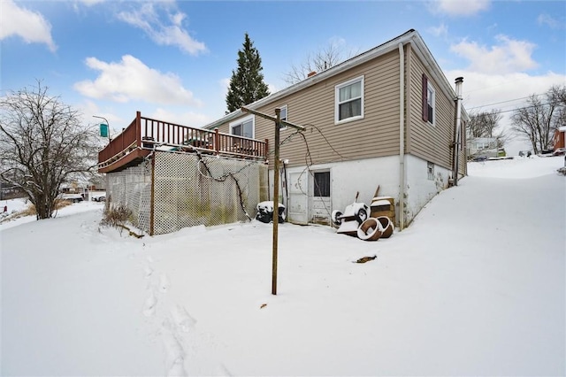 snow covered back of property featuring a wooden deck