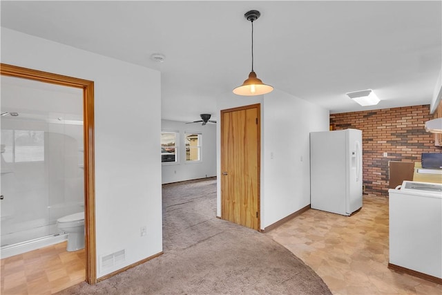 interior space featuring brick wall, ceiling fan, pendant lighting, washer / clothes dryer, and white fridge with ice dispenser