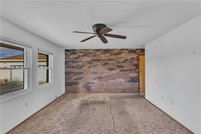 carpeted empty room with ceiling fan and brick wall