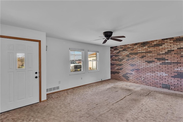 entryway featuring carpet, ceiling fan, and brick wall