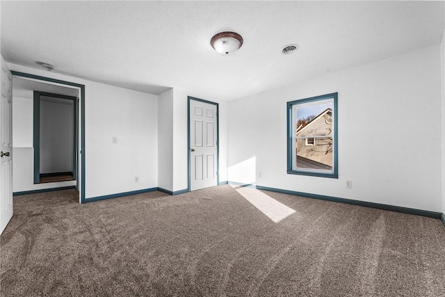 unfurnished room with dark colored carpet and a textured ceiling