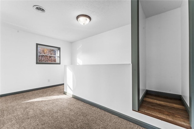 unfurnished room with carpet flooring and a textured ceiling