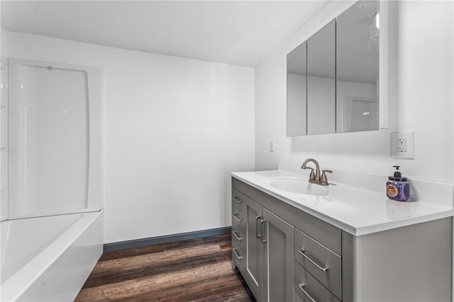 bathroom with a tub to relax in, vanity, and hardwood / wood-style flooring