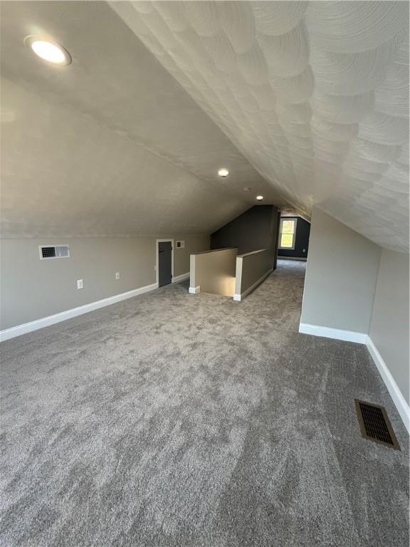 additional living space featuring carpet floors and vaulted ceiling