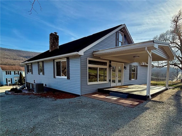 back of house featuring central AC unit, a wooden deck, and french doors