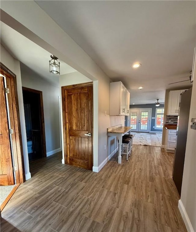 kitchen featuring white cabinets, wood-type flooring, a kitchen bar, and kitchen peninsula