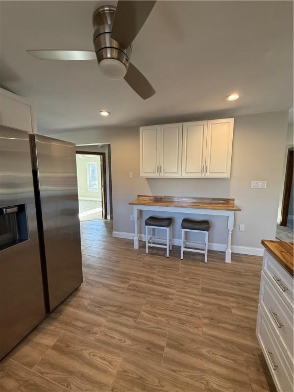 kitchen featuring white cabinets, ceiling fan, stainless steel fridge with ice dispenser, and light hardwood / wood-style flooring