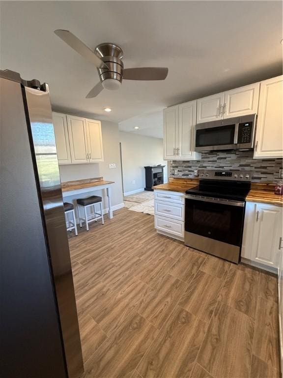 kitchen featuring white cabinets, stainless steel appliances, light wood-type flooring, and wood counters