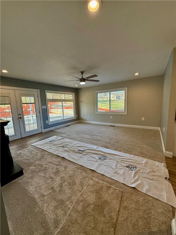 unfurnished living room with french doors, carpet floors, plenty of natural light, and ceiling fan