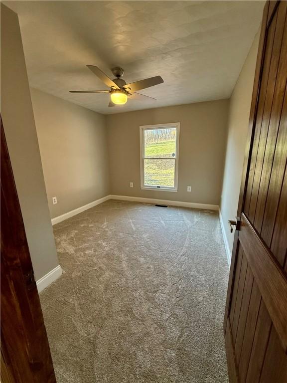 carpeted spare room with ceiling fan